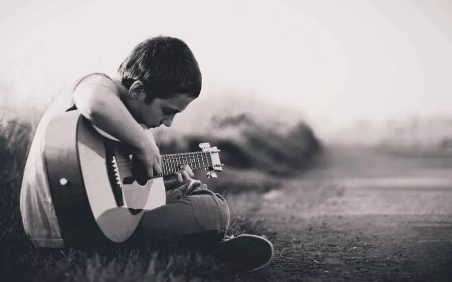 Criança tocando violão aprendendo as primeiras posições